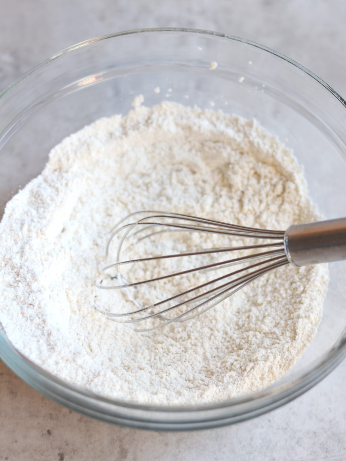 Whisking dry ingredients for pancakes in a glass bowl.