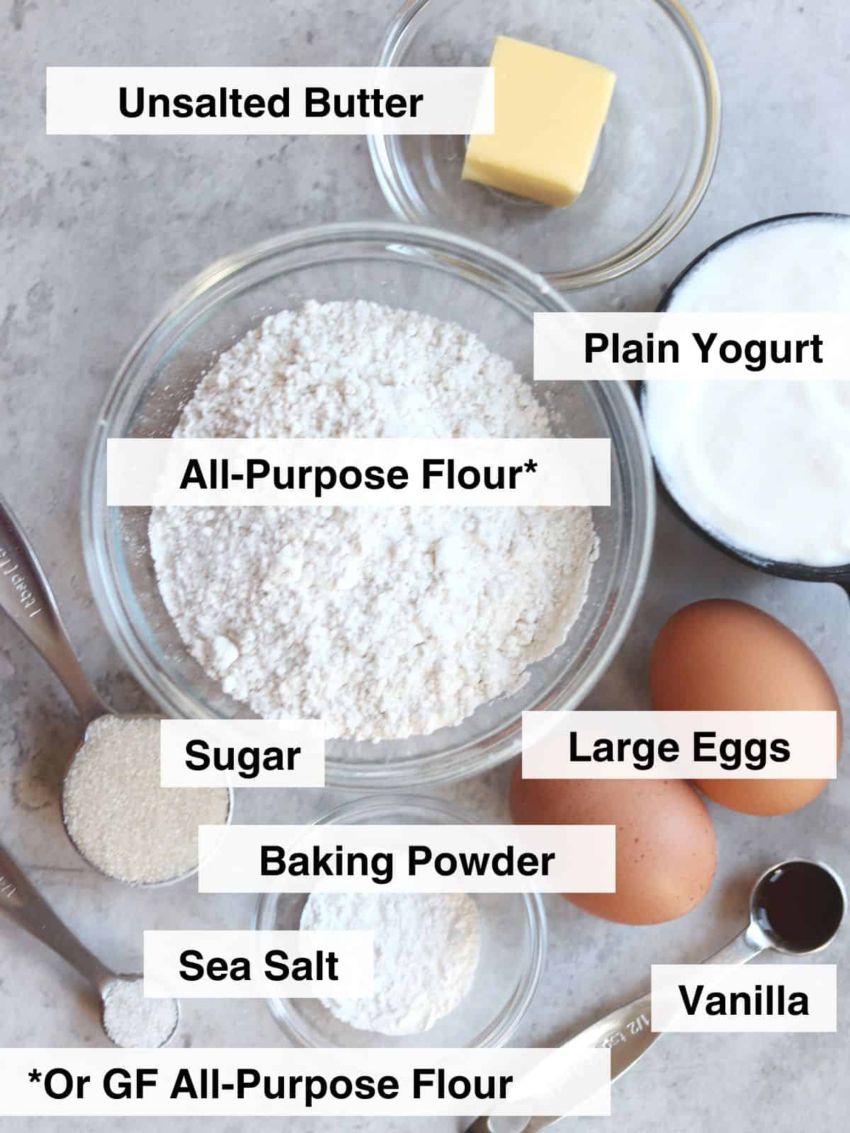 Ingredients for mini pancakes with yogurt arranged on a concrete countertop.