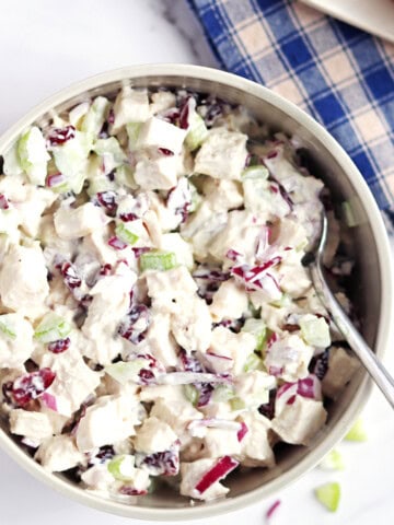 Homemade cranberry chicken salad in a tan ceramic serving bowl.