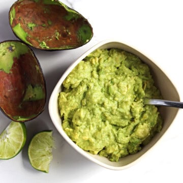 Homemade guacamole in a tan serving dish.