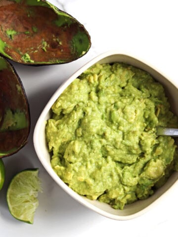 Homemade guacamole in a tan serving dish.