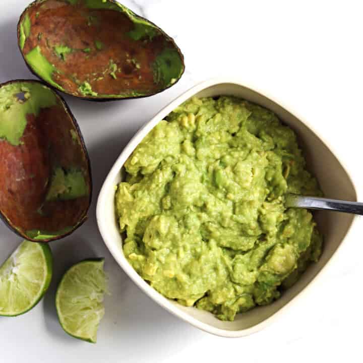 Homemade guacamole in a tan serving dish.