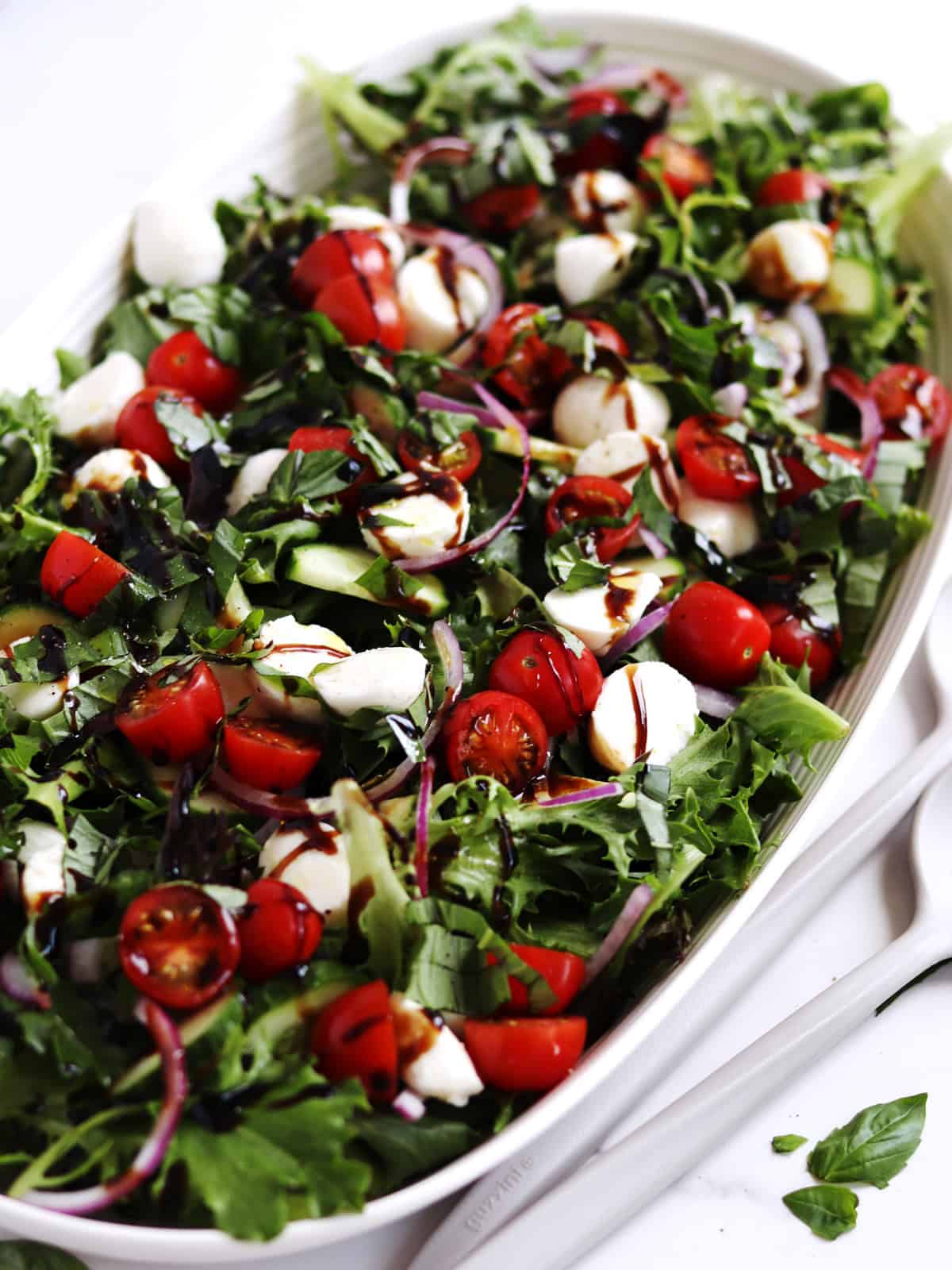 Closeup of Caprese chopped salad on a beige ceramic serving platter.