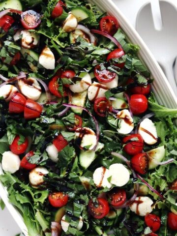 Caprese chopped salad on a beige ceramic serving platter.