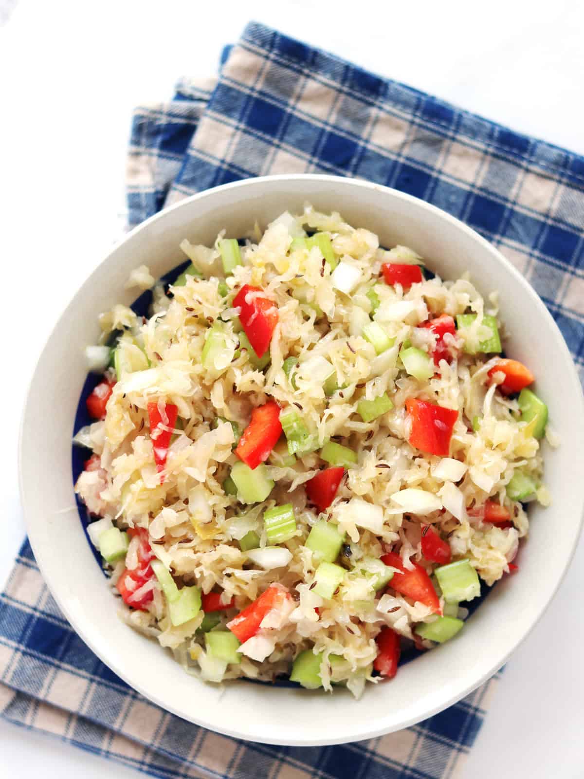 Old fashioned sauerkraut salad with caraway seeds in a tan and blue serving bowl.