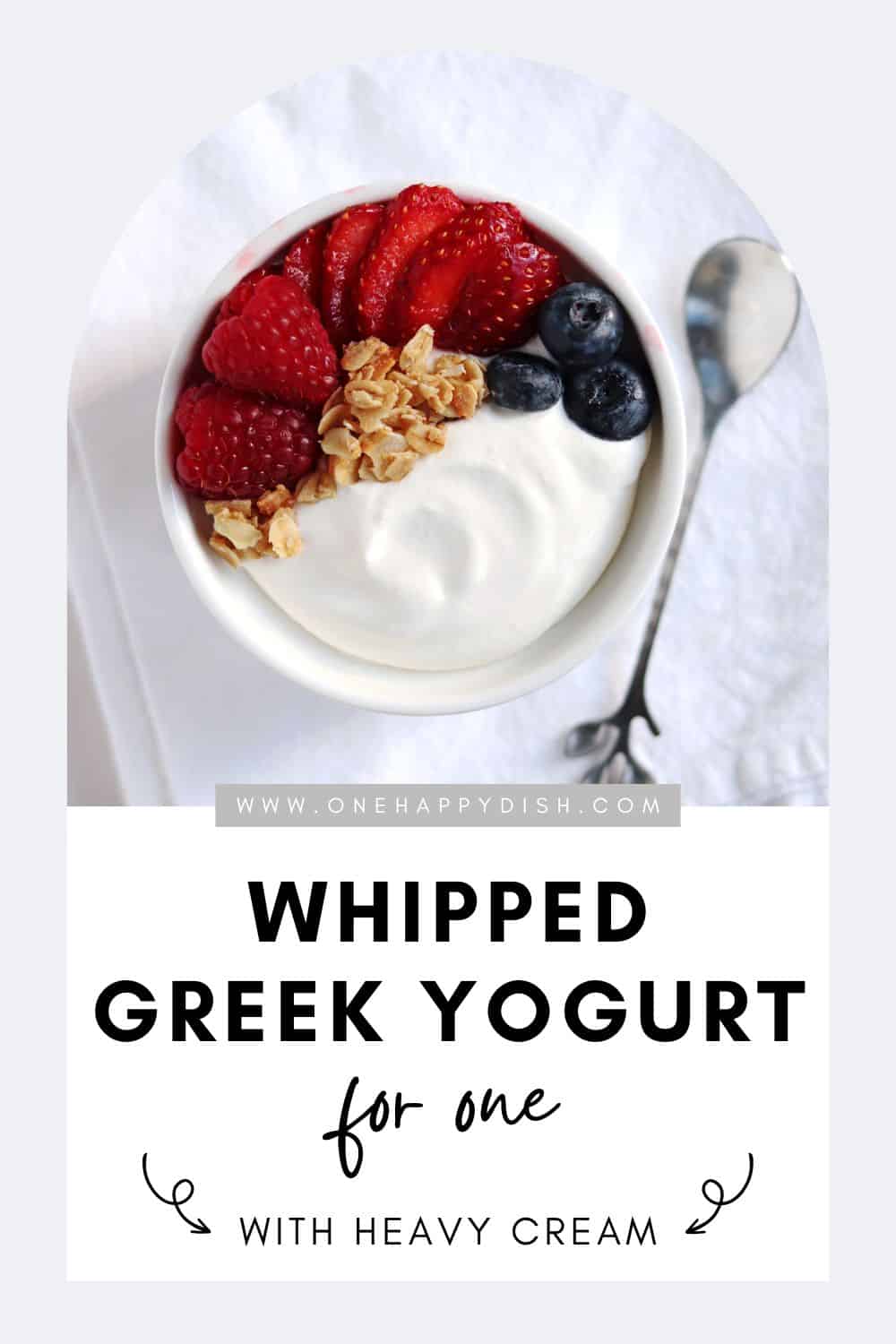 Whipped Greek yogurt in a serving dish topped with mixed fresh berries and granola.
