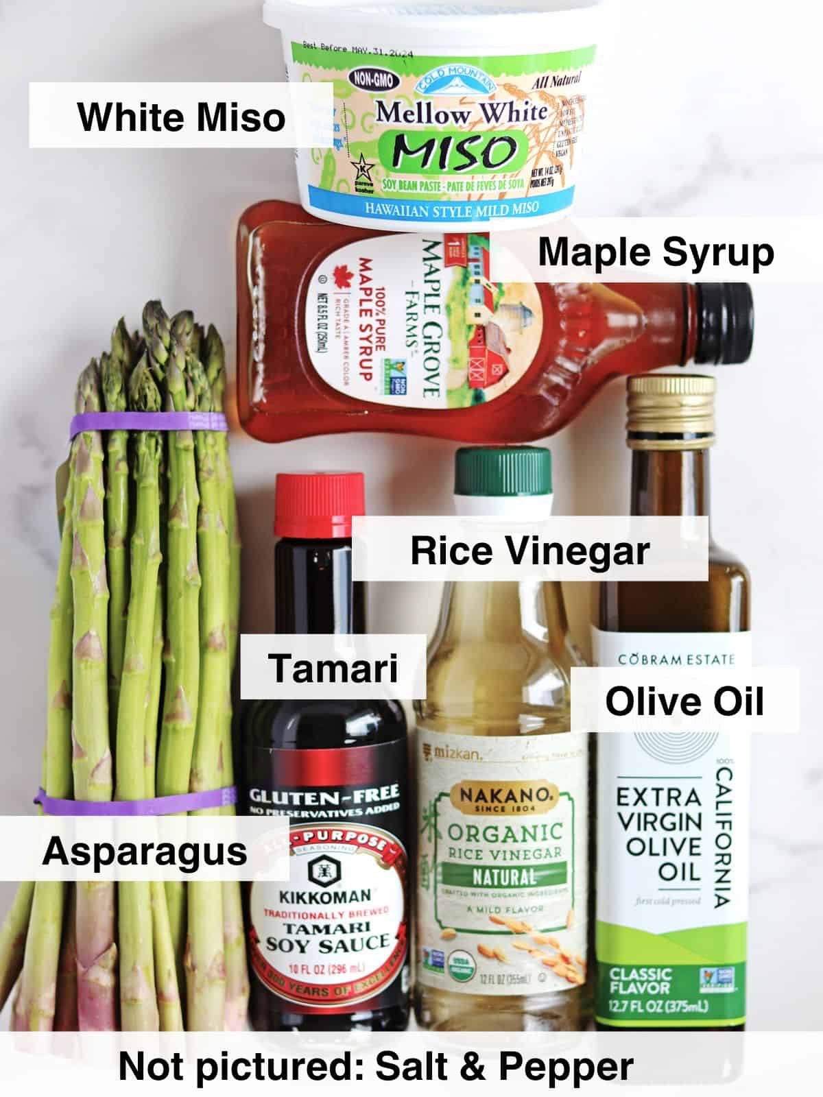 Ingredients for roasted asparagus with maple miso glaze arranged on a white marble countertop.