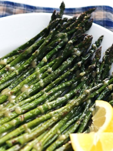 Oven roasted asparagus with maple miso glaze on a white plate.