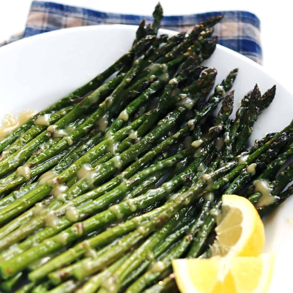 Oven roasted asparagus with maple miso glaze on a white plate.