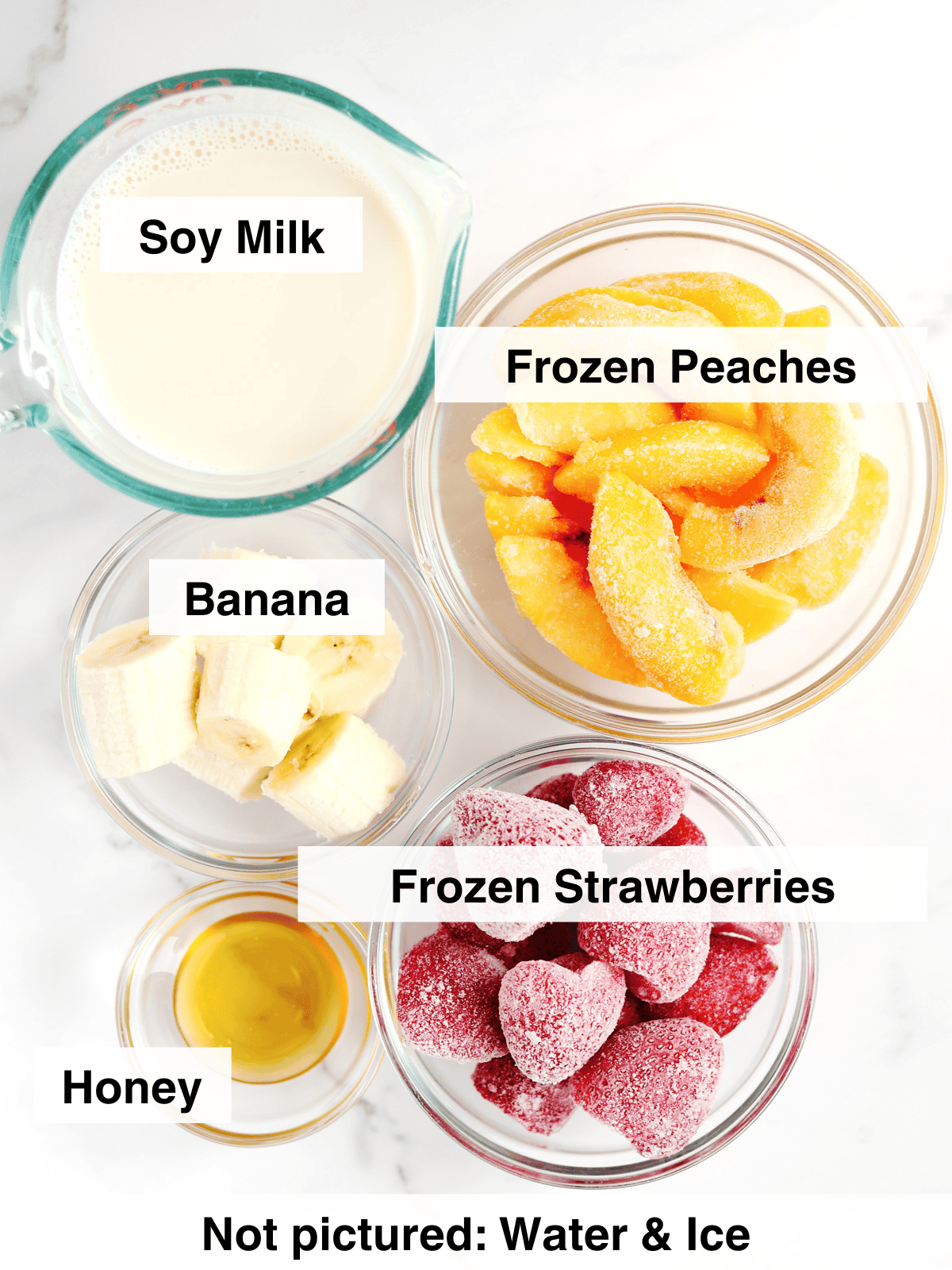 Strawberry peach smoothie ingredients in glass meal prep bowls on a white marble countertop.