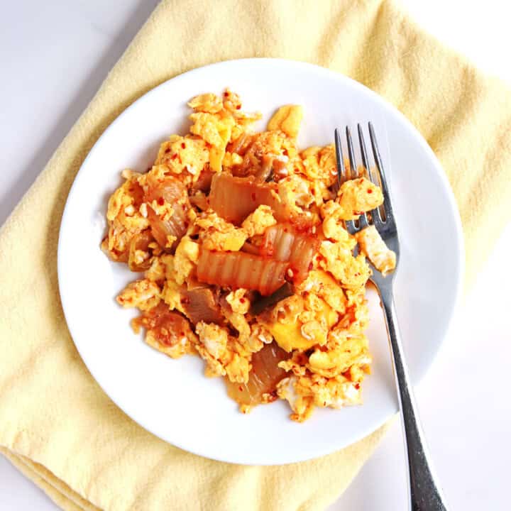 Kimchi scrambled eggs on a white plate.