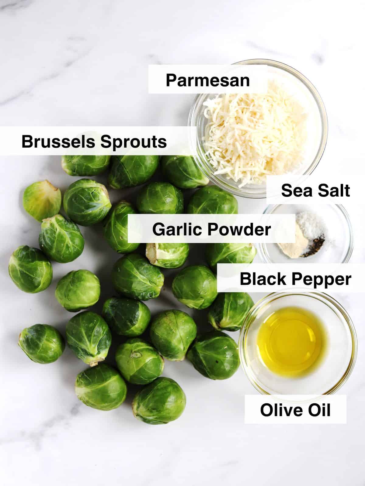Ingredients for Parmesan crusted Brussels sprouts arranged on a white marble countertop.