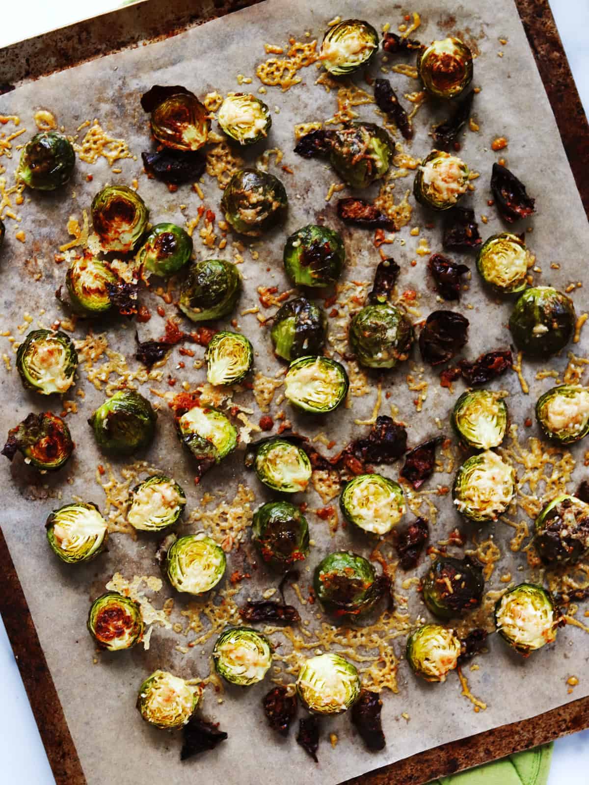 Parmesan crusted Brussels sprouts on a parchment paper lined baking sheet.