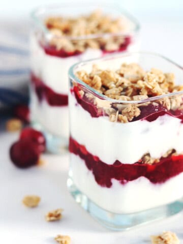 Cranberry yogurt parfaits in glass yogurt jars.