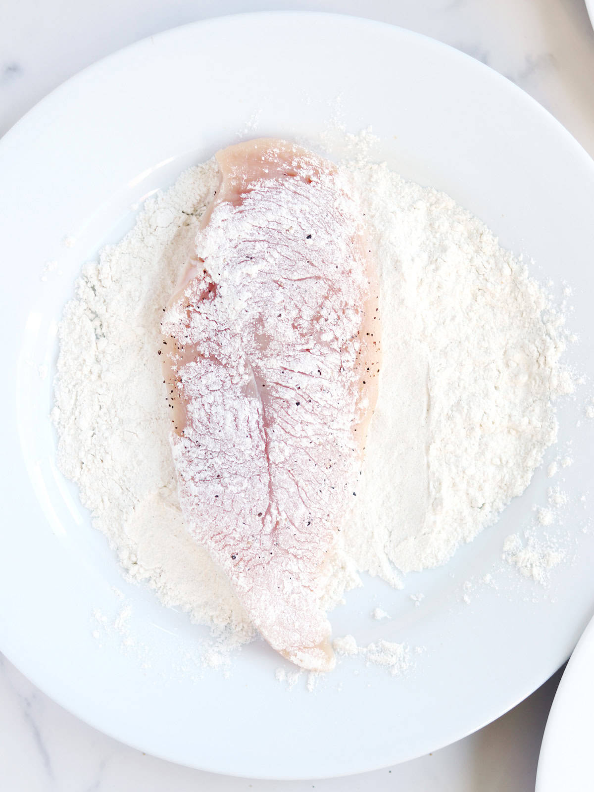 Dredged chicken breast on a white plate