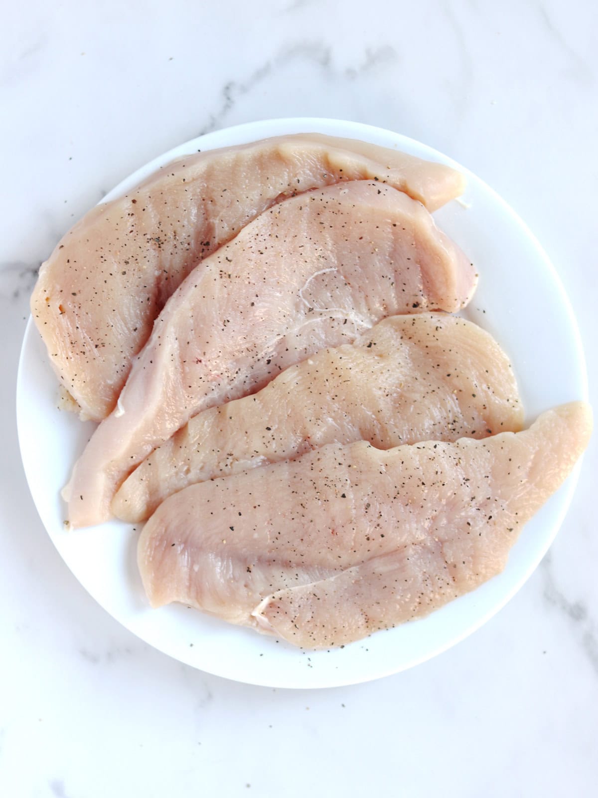 Thin sliced chicken breasts seasoned with salt and pepper.