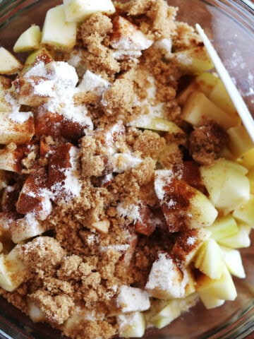 Apple crisp filling ingredients in a glass mixing bowl.