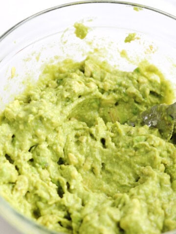 Freshly mixed guacamole in a glass bowl.