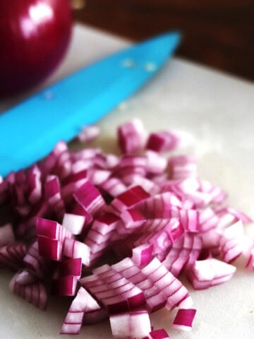 Diced red onion on a white cutting board.