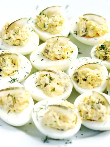 Dill pickled deviled eggs on a white serving plate.