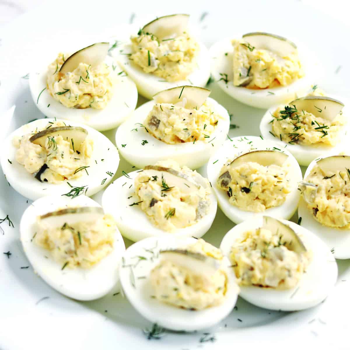 Dill pickled deviled eggs on a white serving plate.