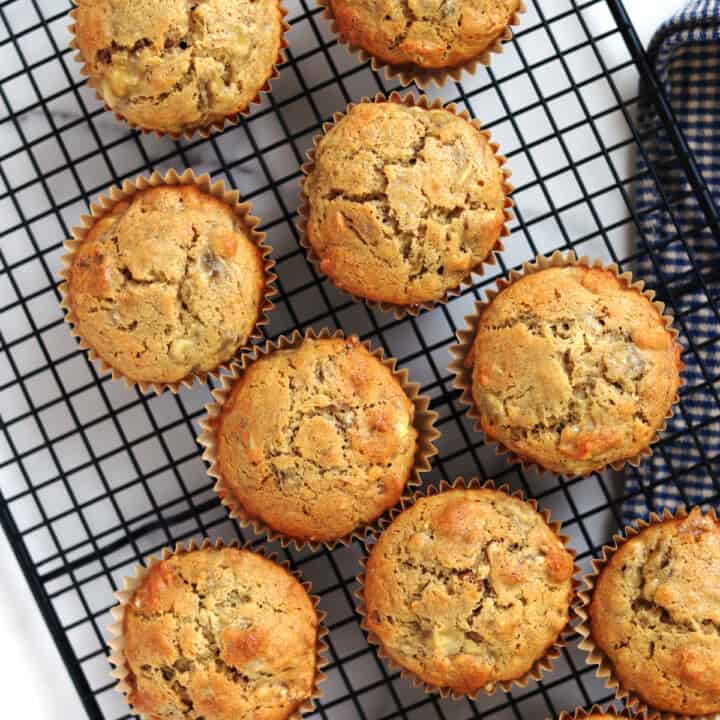 Freshly baked banana walnut muffins on a black wire rack.