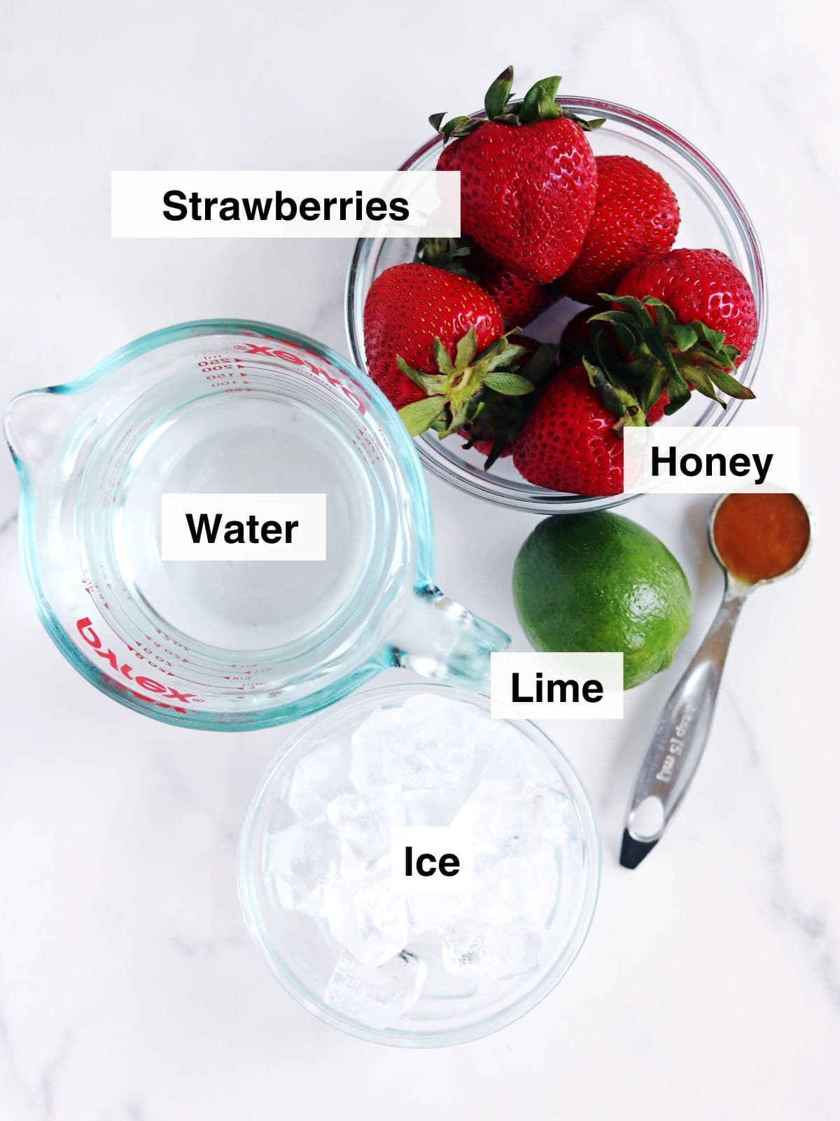 Ingredients for strawberry aguas frescas arranged on a white countertop.