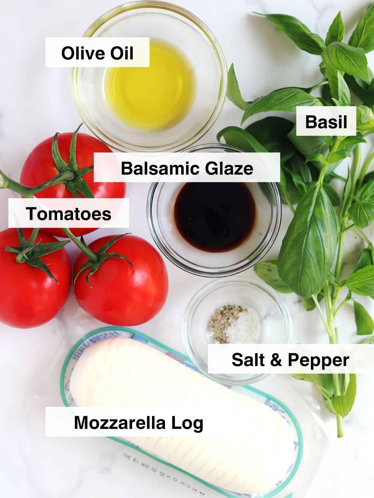 Ingredients for Caprese salad arranged on a marble countertop.