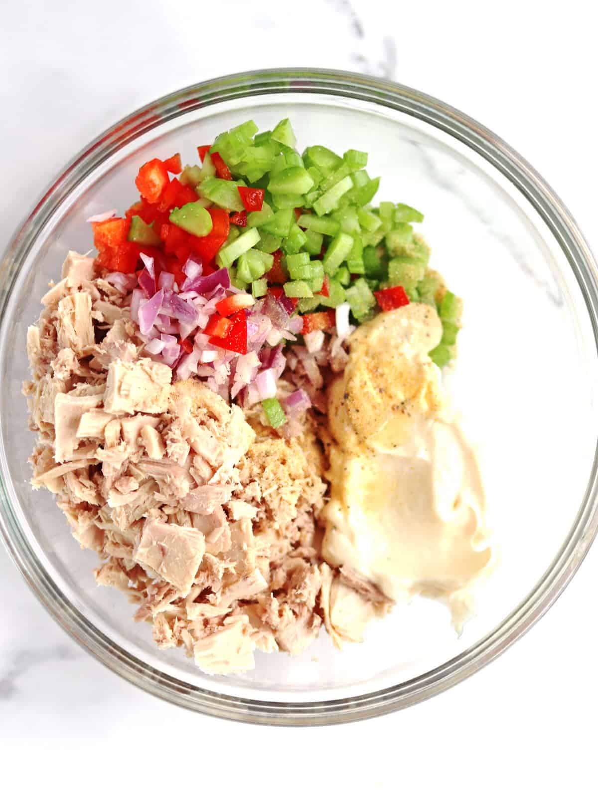 Tuna salad ingredients in a glass mixing bowl.