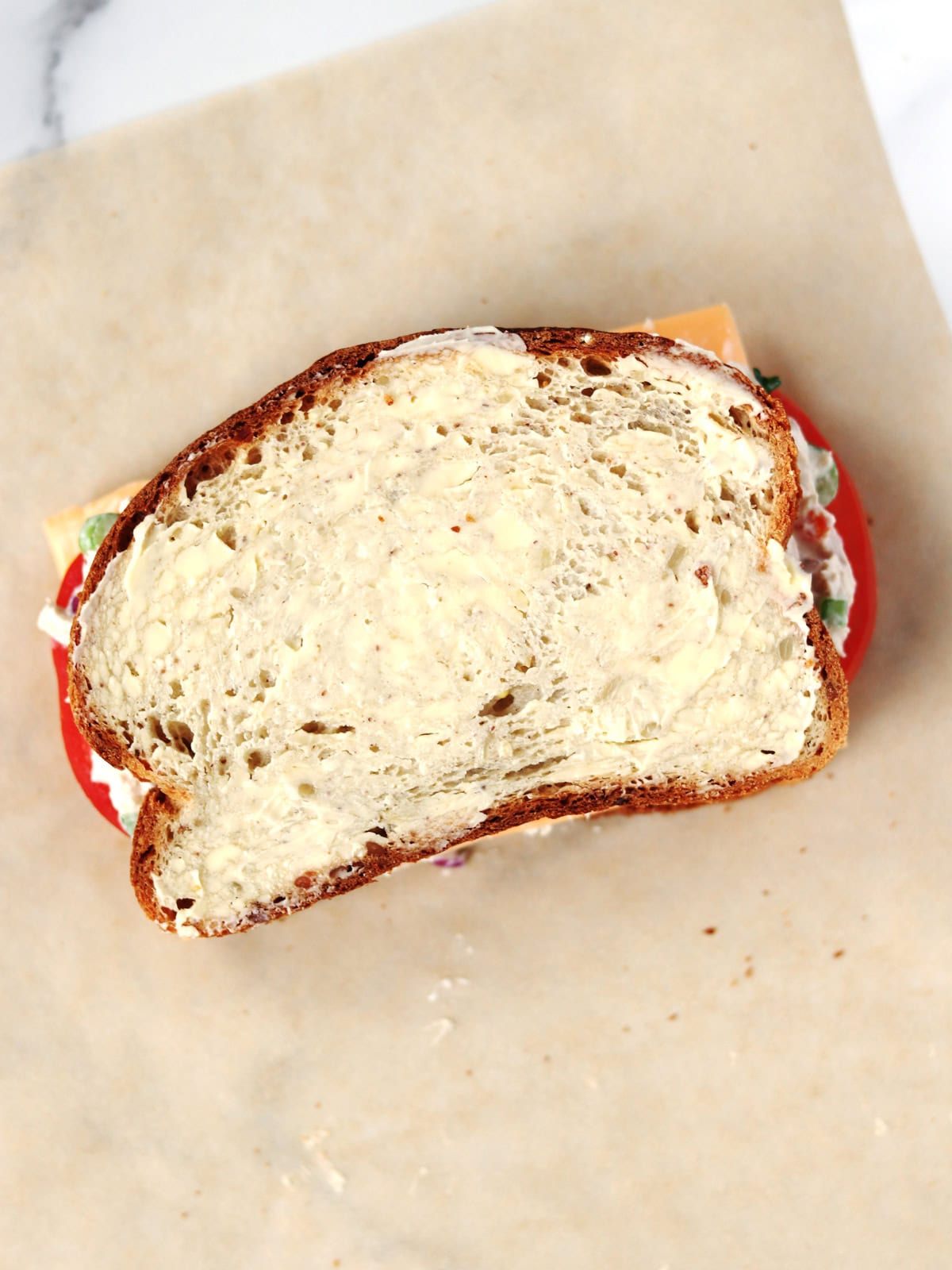 A tuna melt sandwich ready for grilling, placed on parchment paper.